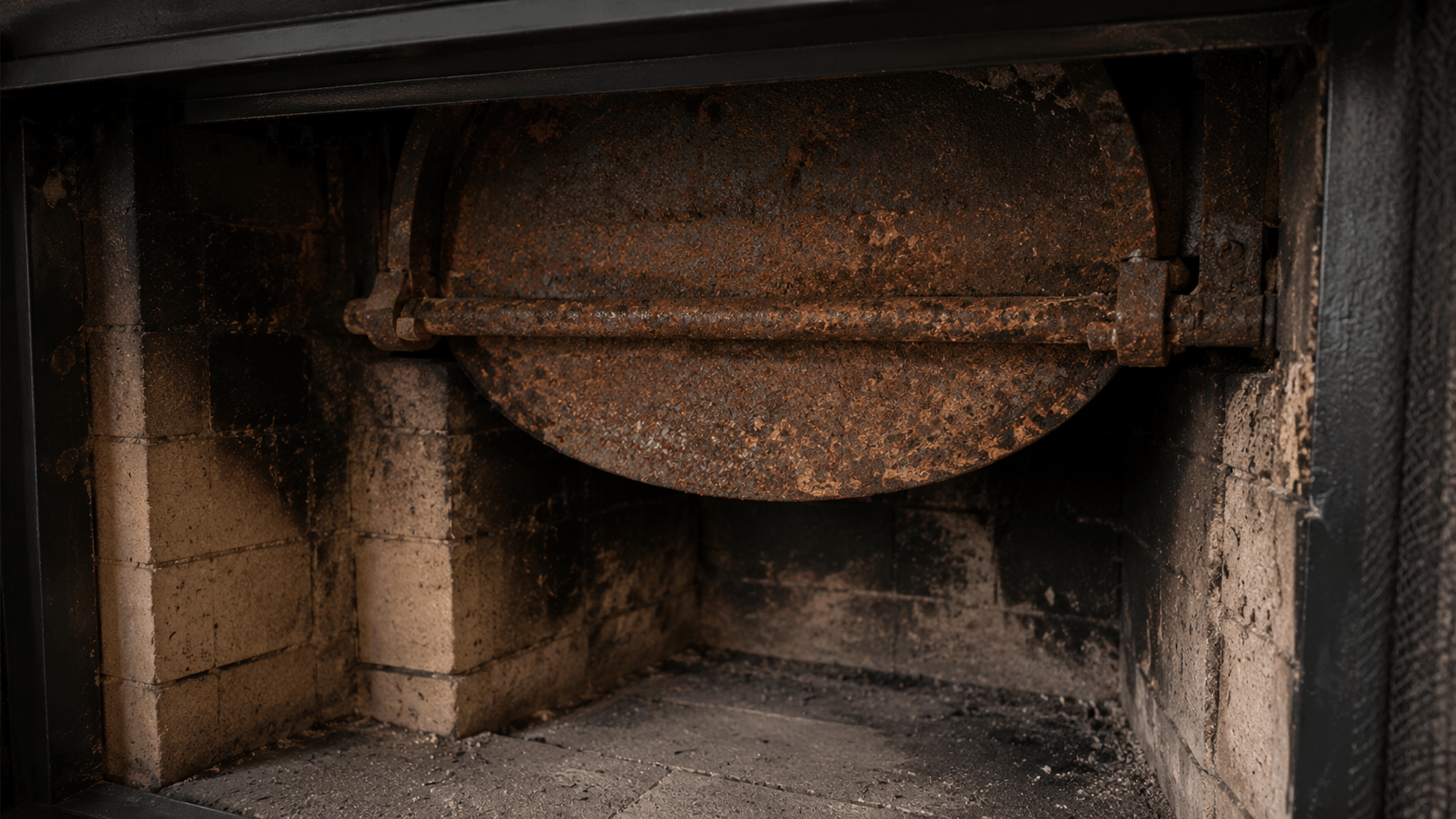 Rusty fireplace damper inside a soot stained brick firebox