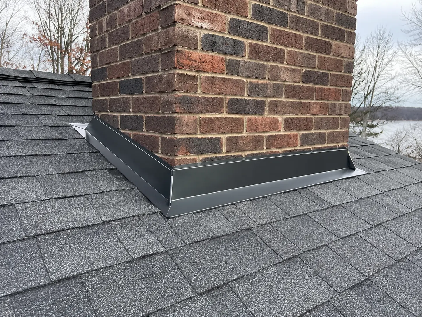 Step and counter flashing layered against the side of a brick chimney